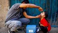 A health worker gives a child polio vaccine in Afghanistan. (Image: Hedayatullah Amid)