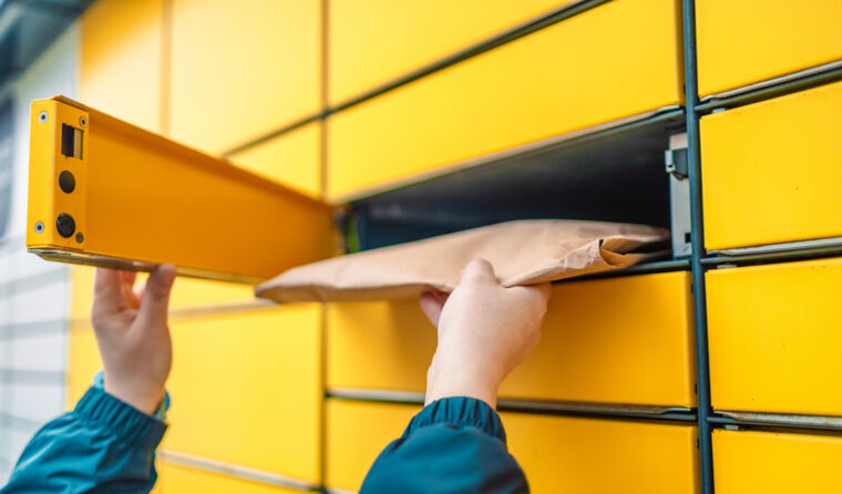 A woman's hands retrieve a package from a postbox