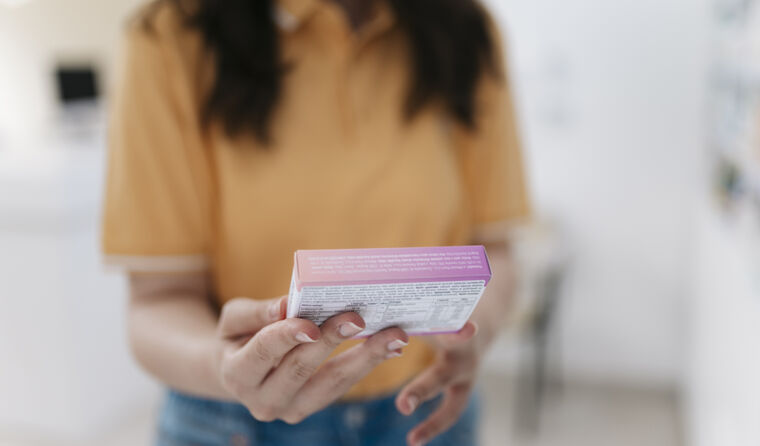 Woman holding medication box reading label