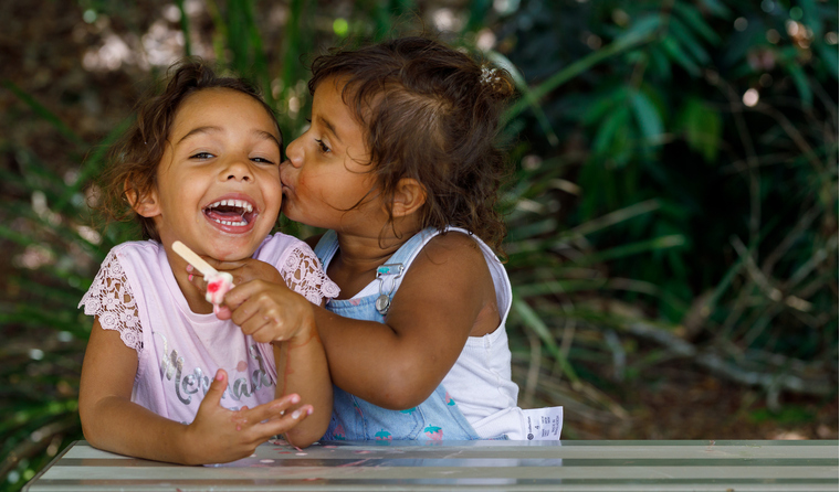 Two young Aboriginal girls eating ice-cream.