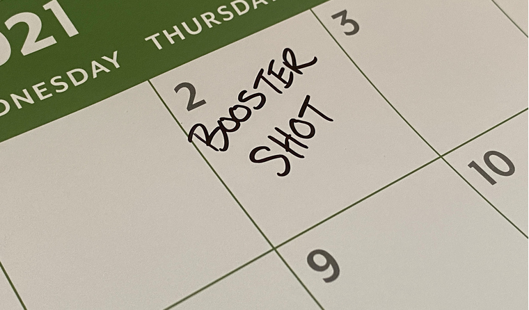 A calendar with the words ‘booster shot’ marked.