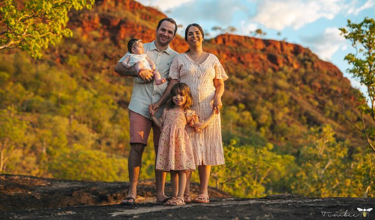 Family standing in a bush setting.