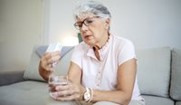 An elderly woman assessing her medication.