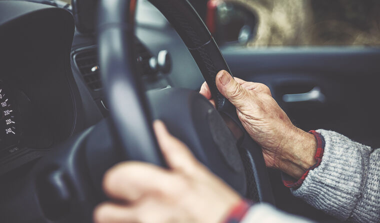 Elderly male hands holder car steering wheel.