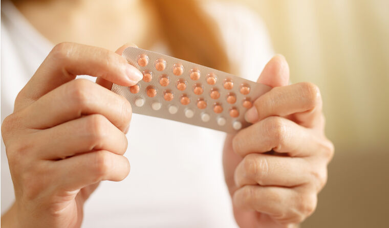 A woman holding pack of contraceptives.