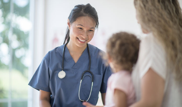 A young female doctor smiles at mother and child.