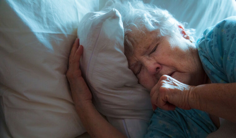Older woman coughing in bed sick