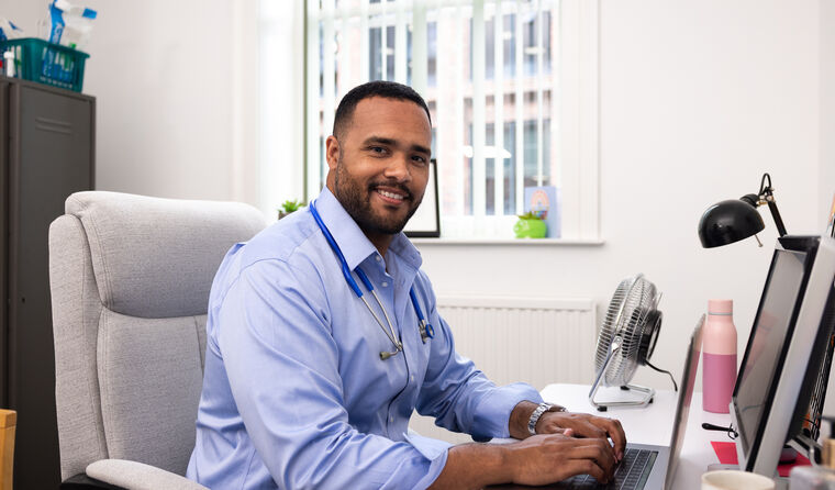 Male GP smiling at desk