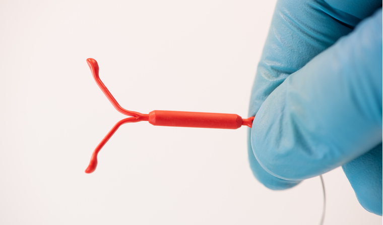 A gloved hand holding an IUD.