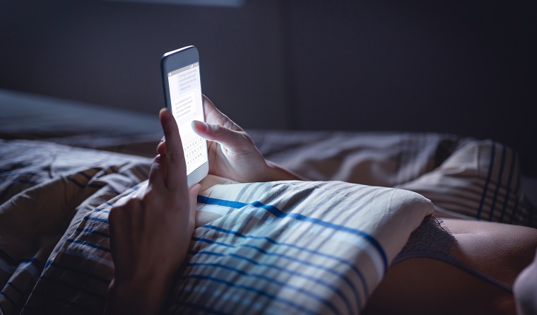 Person in bed looking at phone in the dark
