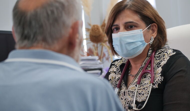 Doctor in a COVID mask consulting with a patient.