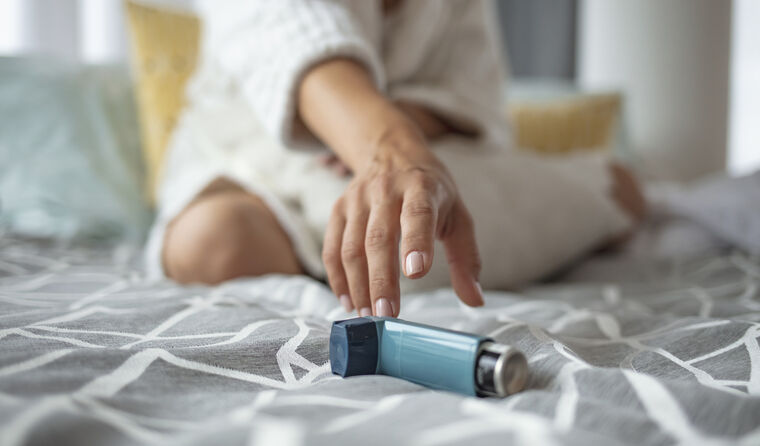 A young woman's hand reaches for asthma inhaler 