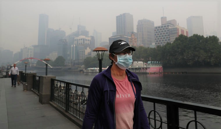 Woman wearing face mask walking through haze.