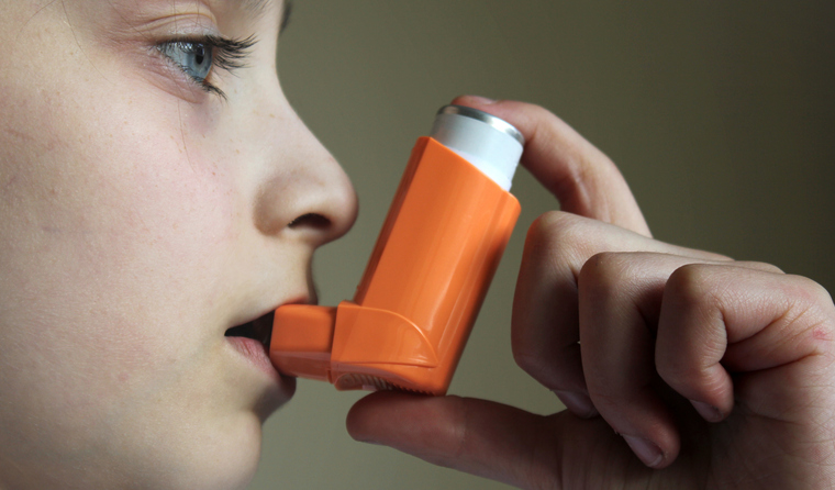 A child using an orange inhaler.