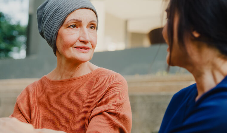 A middle-aged woman with cancer speaks to doctor.