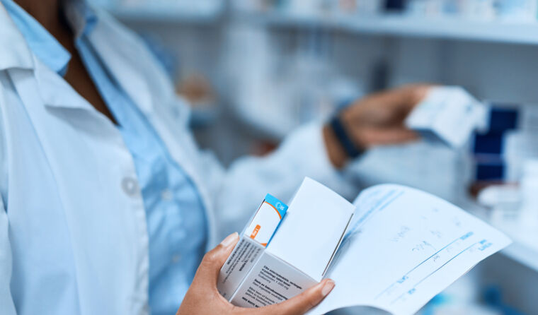 A pharmacist holding medication and prescription.