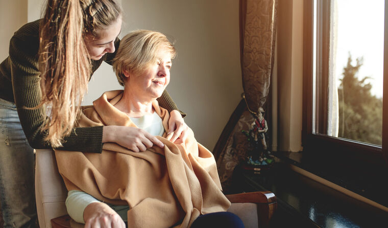 Young woman tends to middle-aged woman in chair