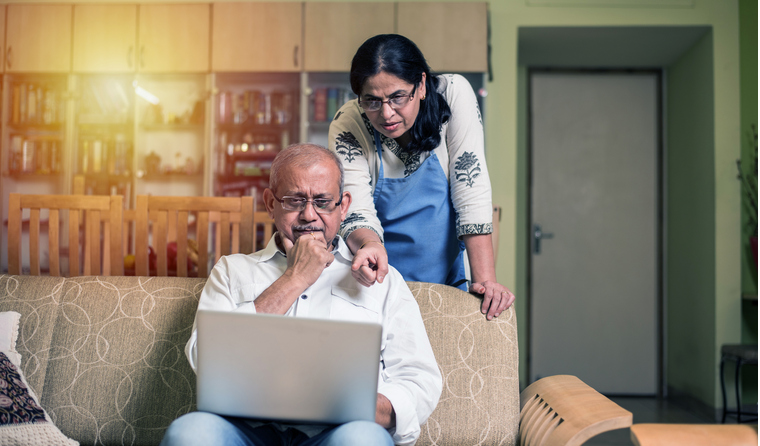 Confused south-Asian couple looking at laptop.