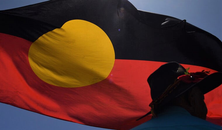 Man standing in front of Aboriginal flag.