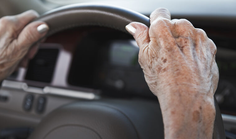 Old person's hands on car steering wheel