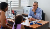 Doctor sits opposite Aboriginal woman and child.