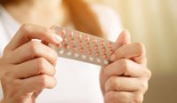 A woman holding pack of contraceptives.