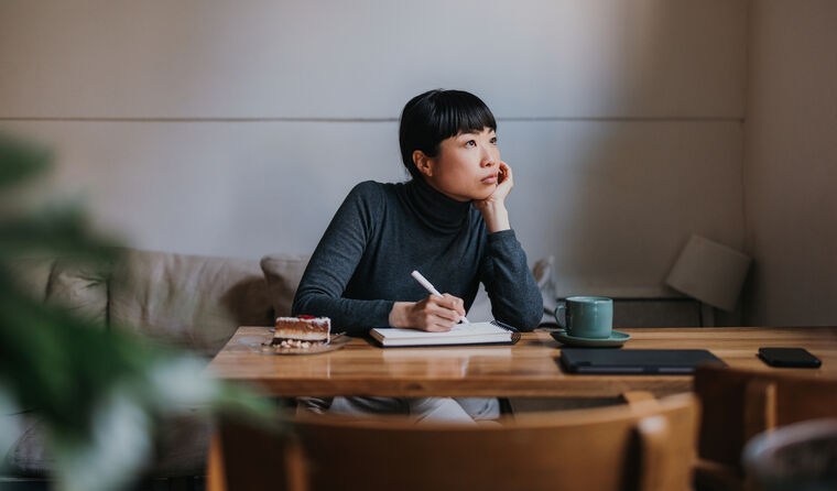 Young woman sits at a desk looking distracted.