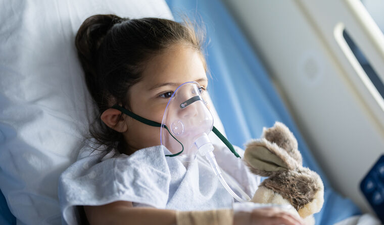 Young girl in hospital bed with oxygen mask