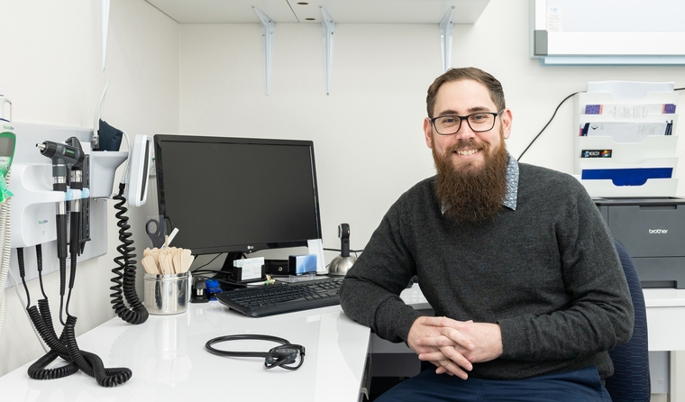 GP Dr Josh Stevens sitting at his desk.