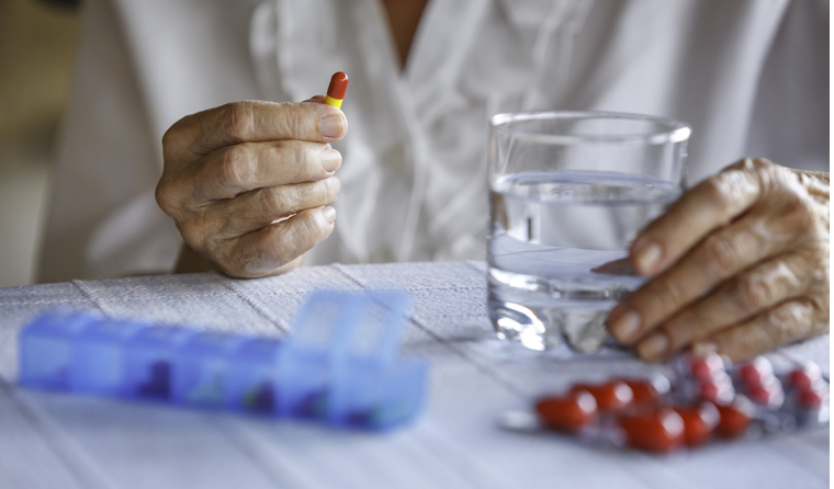Older woman holding a pill.