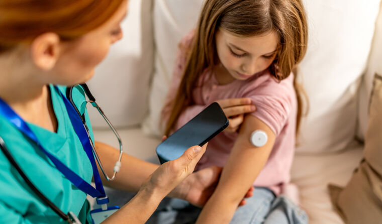 Doctor checks on young girl's CGM device.