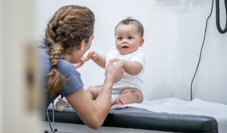 Female doctor holds little baby's hands
