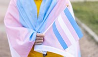 Person wrapped in transgender flag.