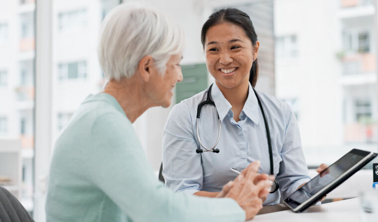 Woman with grey hair faces smiling young doctor.