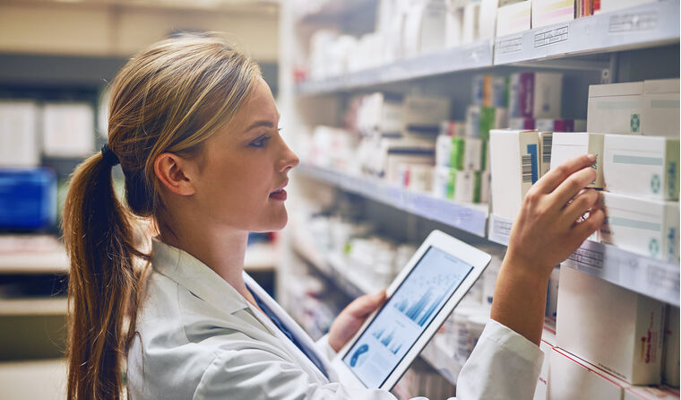 A pharmacist going through medicine on the shelf.