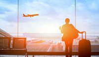 A person at an airport watching a plane take off.