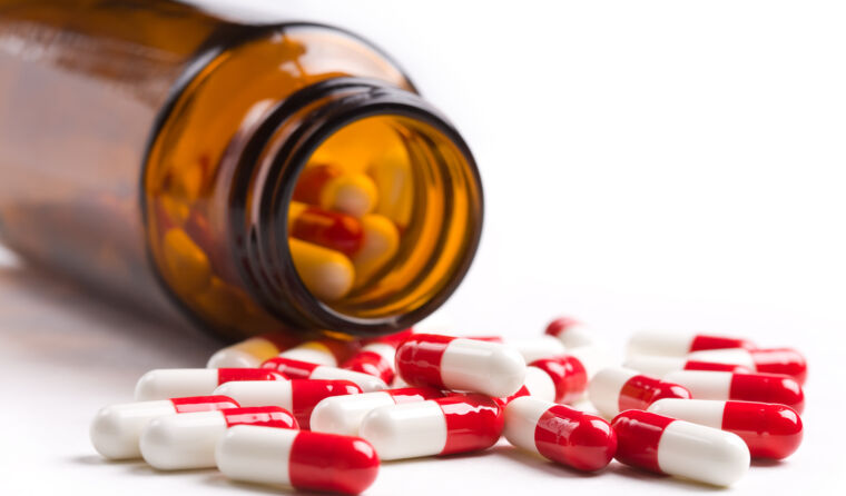 Pill bottle with red and white pills spilling out.