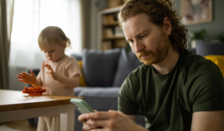 A man receiving a text with a child