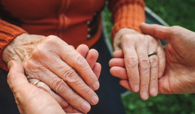Elderly hands being held.