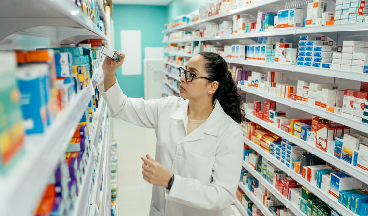 Female pharamacist searches shelves of meds.