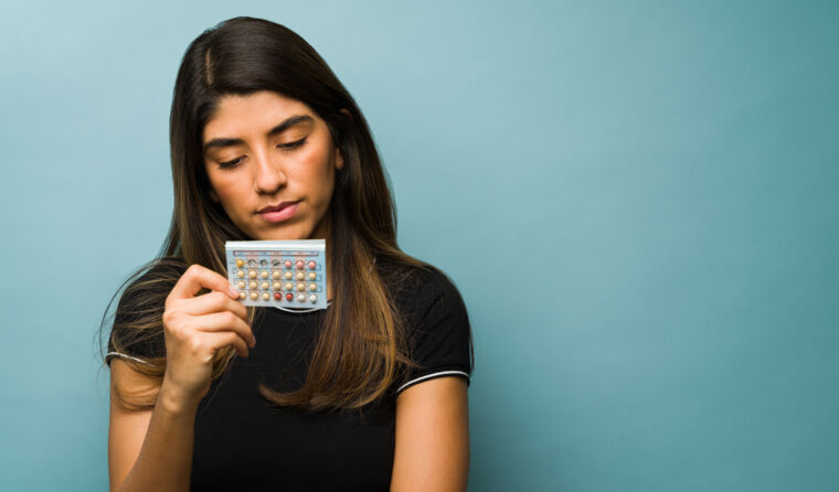 A young woman reads medication packaging.