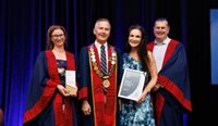 Four people on stage receiving awards