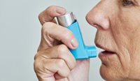 Closeup of senior woman using inhaler.