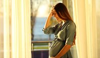 A pregnant woman standing in front of a window.
