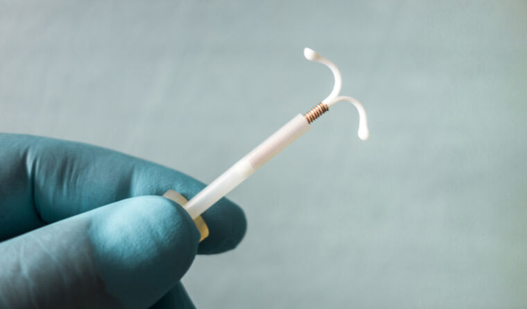 Hand holding IUD.