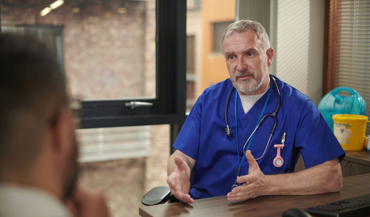 White-haired doctor with patient seen from behind