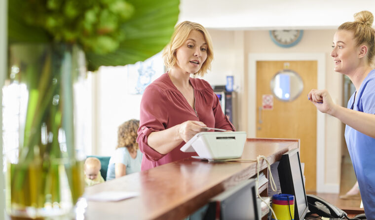 A medical receptionist speaking with a patient.
