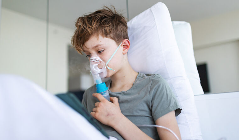 Young boy in hospital bed using nebuliser