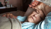 An elderly woman, sick and in bed. 