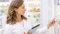 Pharmacist with tablet looking at medicine